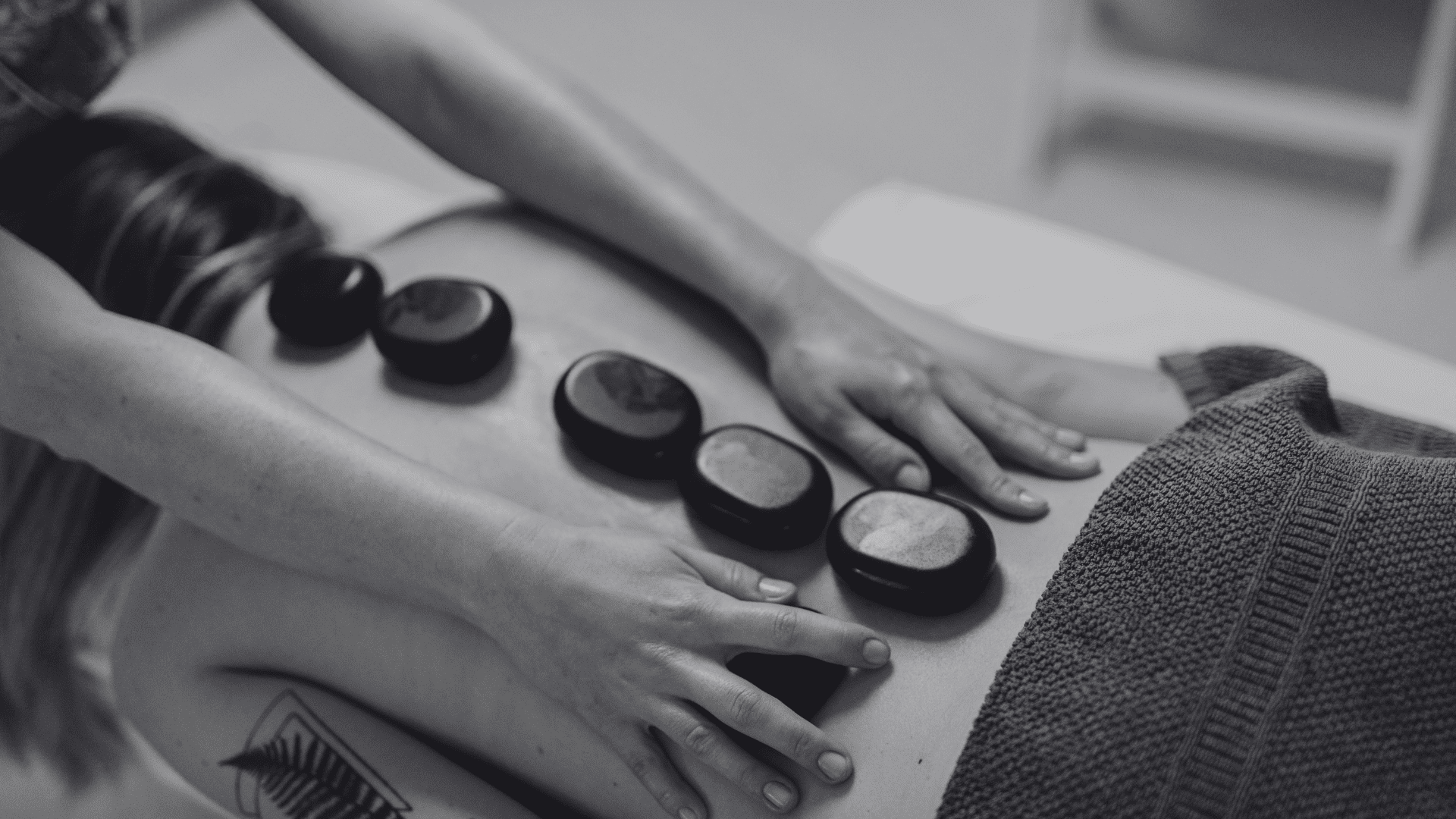 Person receiving a hot stone massage on their back at a spa.