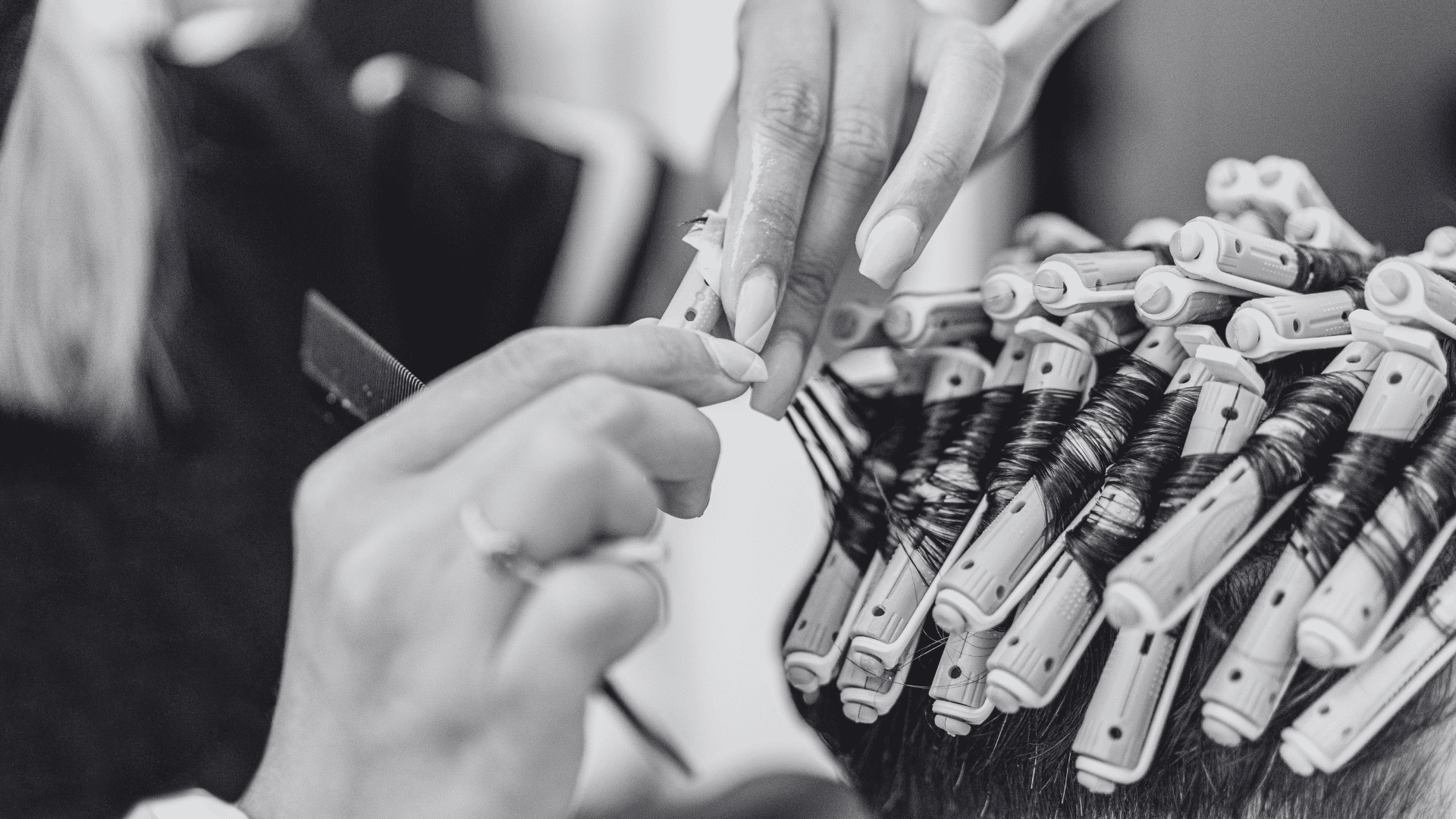 Hairdresser wrapping hair in curlers for a perm treatment. Close-up of hands and tools.