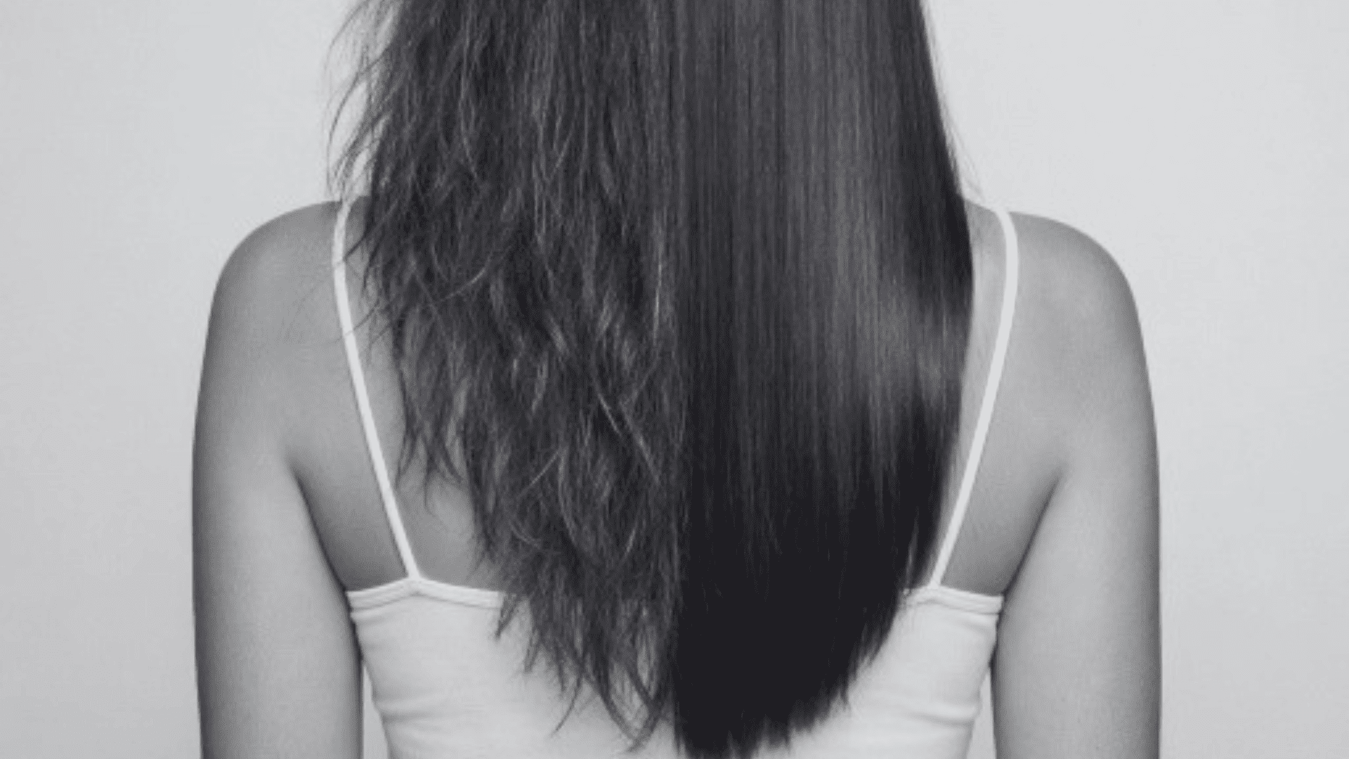Back view of woman with half frizzy, half straight hair, wearing a white tank top.
