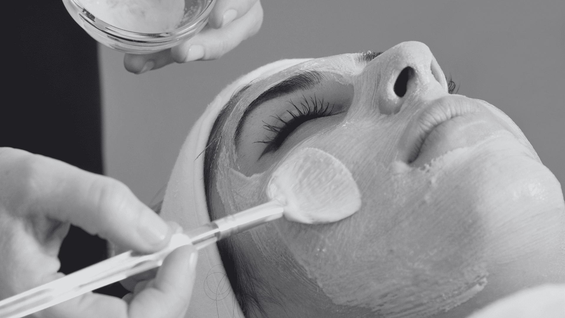 Person receiving a facial treatment, face covered with a mask, eyes closed, and serene expression.