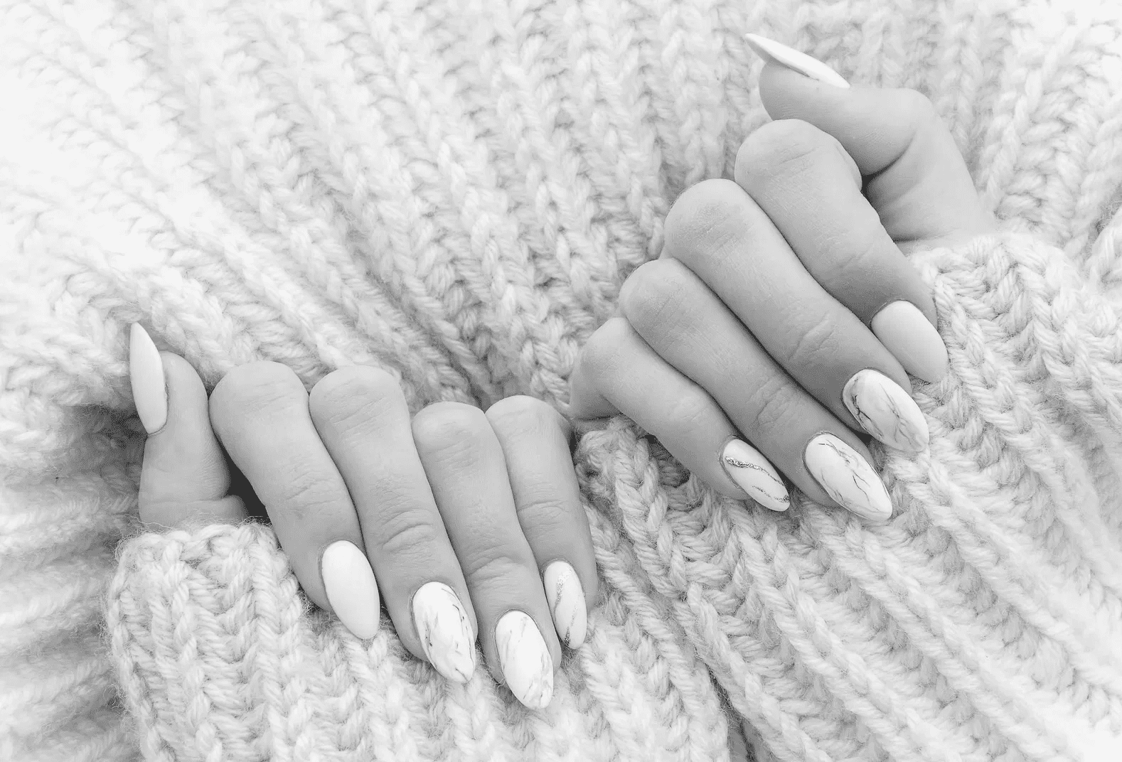 Cozy pink sweater with manicured hands featuring pink and marble nail art.